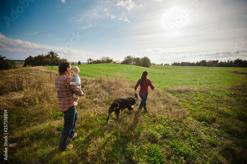 Wallpaper Mural Parents with baby son and dog walking through field Torontodigital.ca