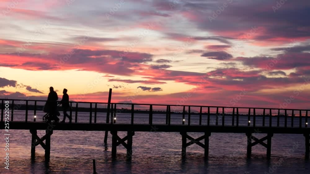 Lesina, Gargano National Park, Apulia, Italy - March 11 2019: people walk on jatty on (lake) lagoon at sunset. Lesina, Gargano National Park, Apulia, Italy - March 11 2019: people walk on jatty on (lake) lagoon at sunset.