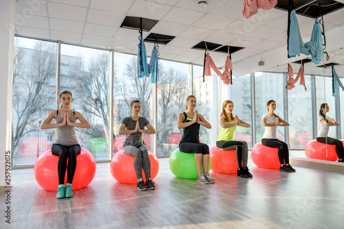 Group of women in gym making exercises on ball