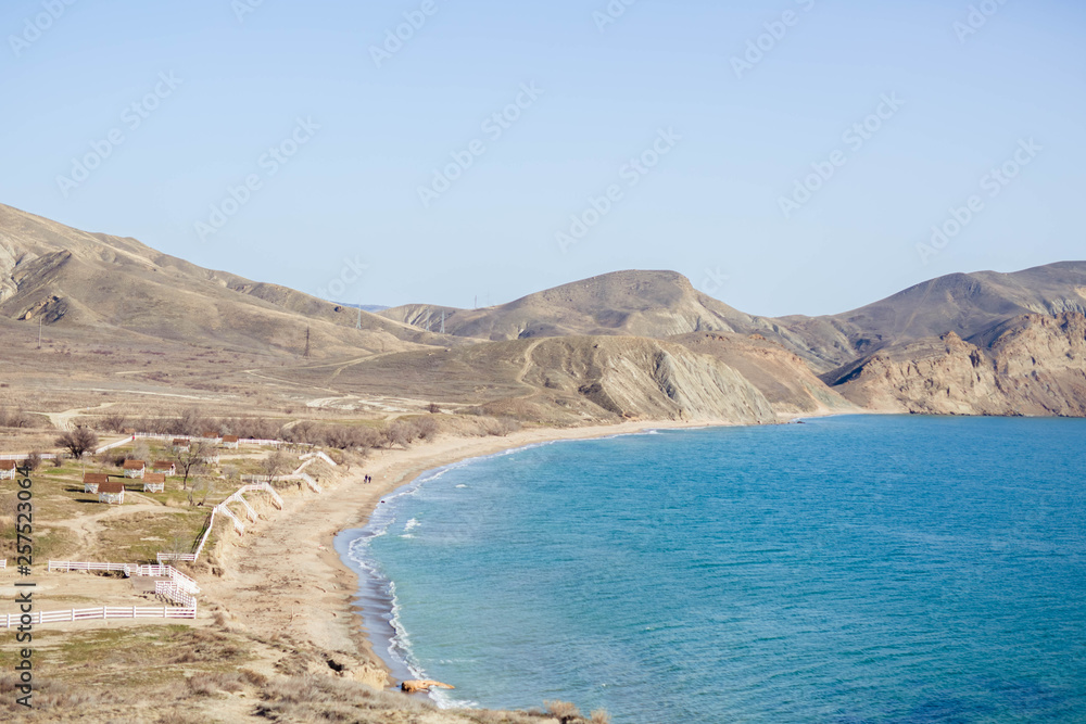 Yellow sand hills with transparent turquoise sea and blue sky. Vacation and travel time.