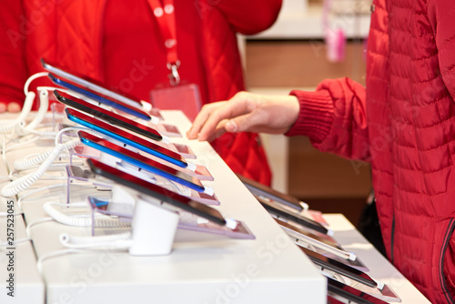 Smartphones on the counter of a electronics store, the seller helps the buyer to choose a product