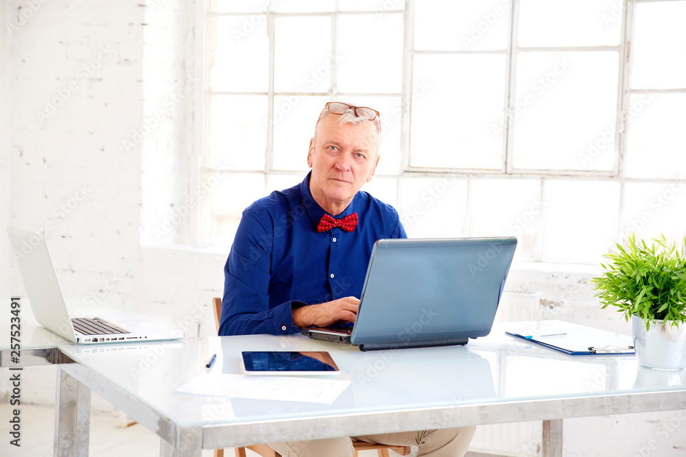 Elderly businessman working on laptop in the office Elderly businessman working on laptop in the office