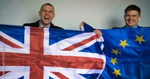 Two young English and European fans in their jackets are holding the English and the European flag in their hands arguing (rejoicing) about how Brexit goes. Concept of: New Year, England vs Europe. photo