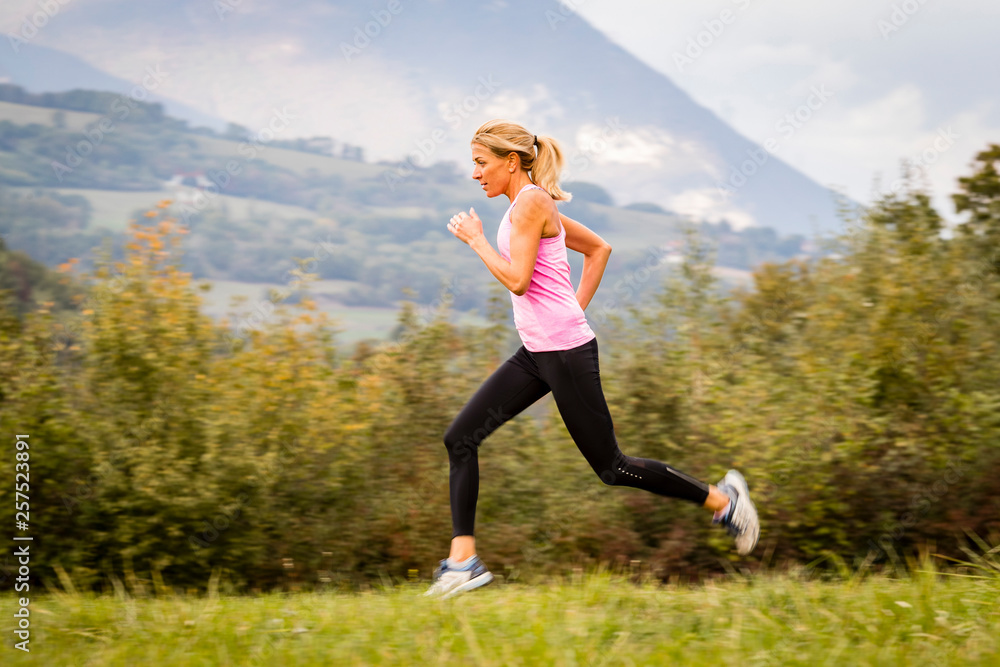 Woman in pink tank top running in meadow Woman in pink tank top running in meadow