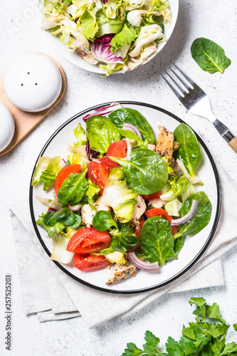 Green salad with chicken and vegetables on white.