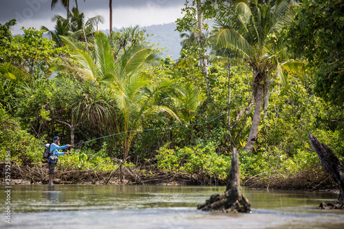 Angler Jonathan Jones casts while fly fishing in Samoa, at a location where a freshwater stream meets the sea in the jungle.
