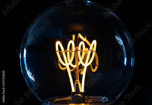 Classic retro incandescent edison light bulb: close up of the glowing filament photo