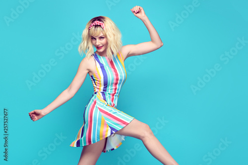 Young fashionable girl Smiling jump in Studio. Beautiful easy-going blonde woman in Stylish summer dress having fun, makeup, Trendy sneakers. Cheerful happy model, funny fashion concept
