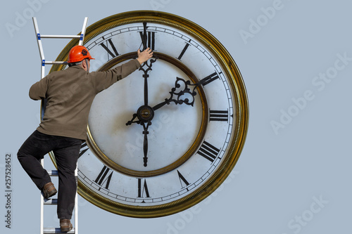 Foto Man is standing on a ladder and adjusting the clock