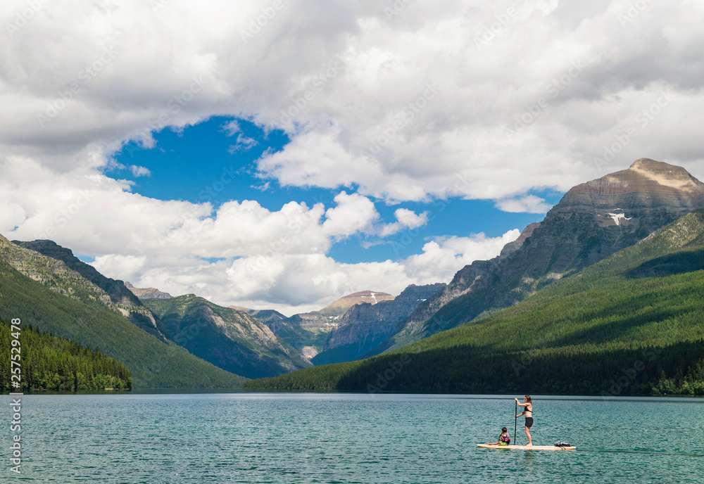 Woman and boy paddle boarding across Bowman Lake Woman and boy paddle boarding across Bowman Lake