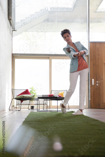 Businesswoman playing golf on artificial turf in a loft photo