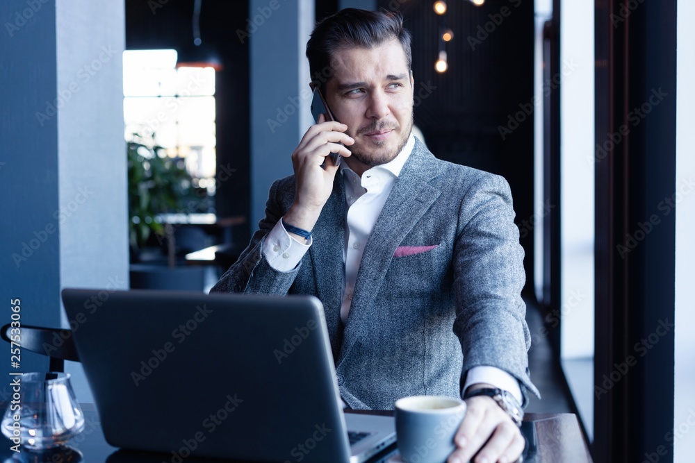 Pensive handsome businessman talking on the phone in cafe and looking away Pensive handsome businessman talking on the phone in cafe and looking away