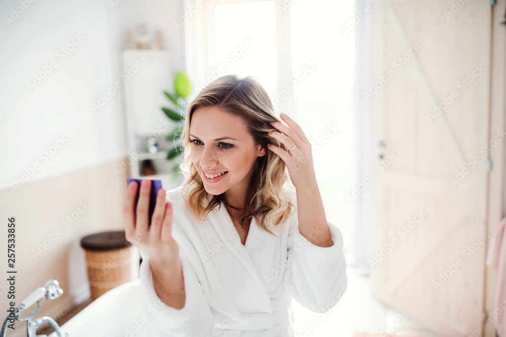 Smiling woman in bathrobe looking in mirror in the morning at home Smiling woman in bathrobe looking in mirror in the morning at home