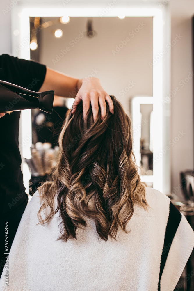 Beautiful brunette woman with long hair at the beauty salon getting a hair blowing. Hair salon styling concept. Beautiful brunette woman with long hair at the beauty salon getting a hair blowing. Hair salon styling concept.