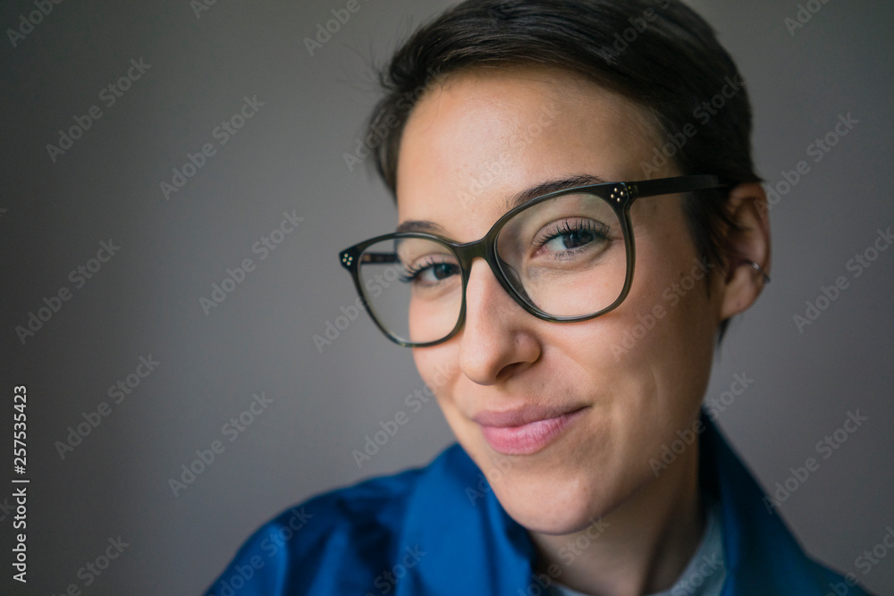Portrait of a smiling young woman with short hair, wearing glasses Portrait of a smiling young woman with short hair, wearing glasses