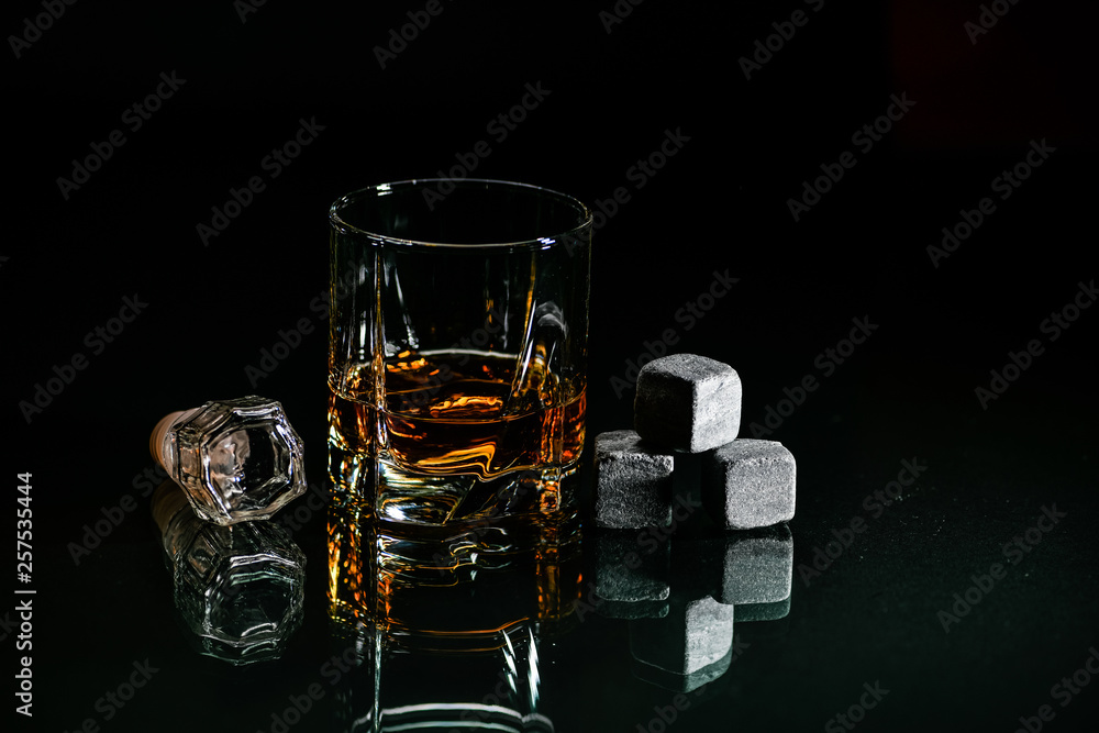 Glasses for whiskey close-up with stones on a glass, isolated on a black background. ice stones, drink in a glass and ice cubes. a set for a dozer and a rest. alcohol