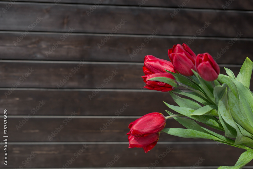 Bouquet of  red tulips  on a dark brown wooden background. Festive concept. Space for copy space.