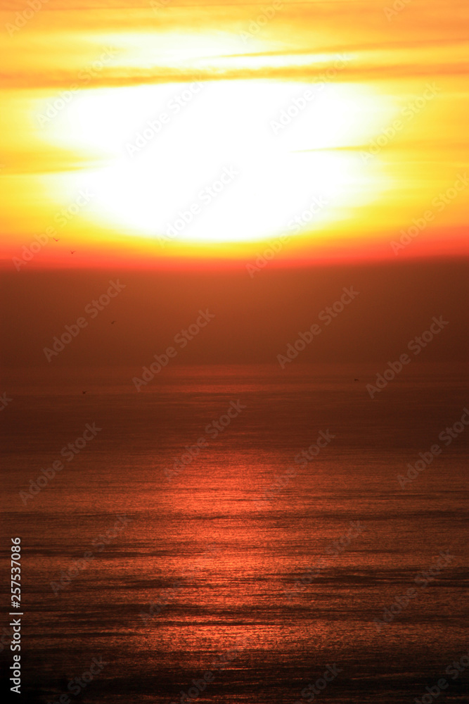 The orange sunset reflected in the small waves. The shimmering waves in the sunset