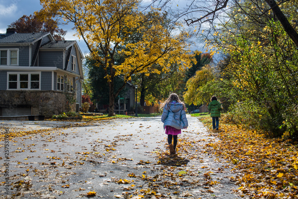 a boy and girl walk down the street together on a windy fall day a boy and girl walk down the street together on a windy fall day