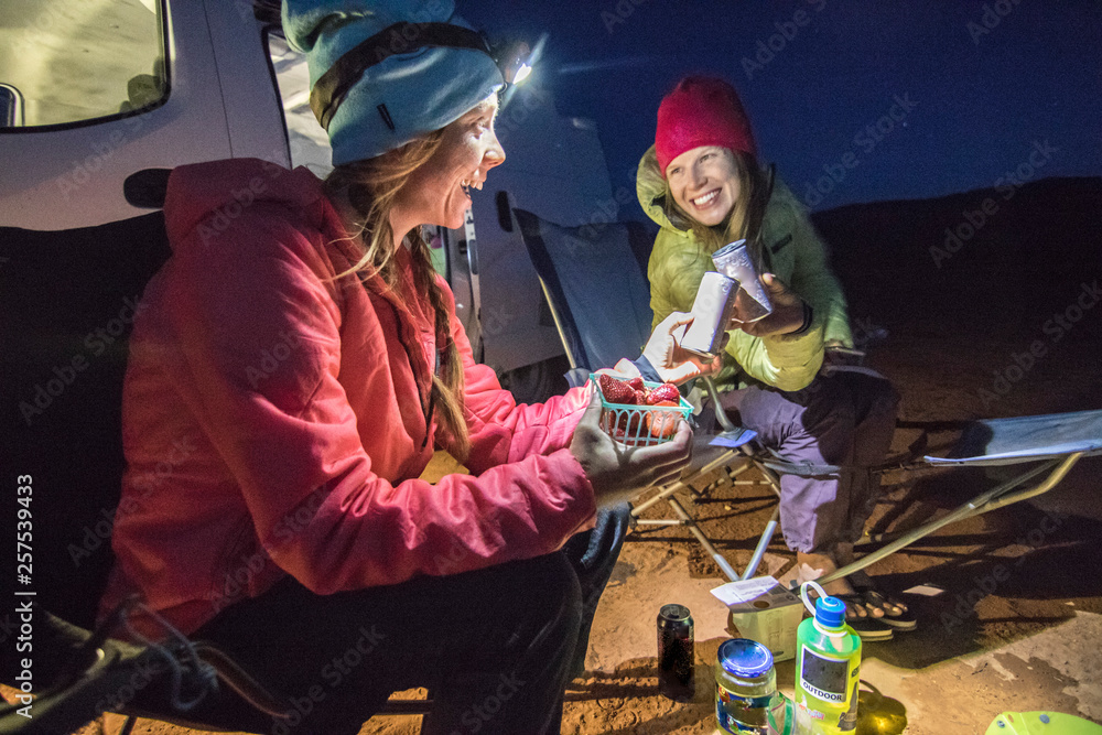 Two women eating while camping in desert, Hole in the Rock Road, Utah, USA Two women eating while camping in desert, Hole in the Rock Road, Utah, USA