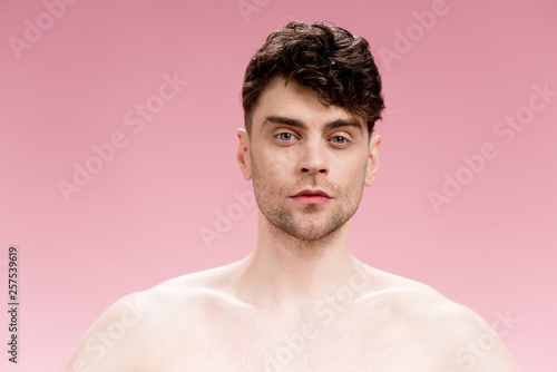 serious and confident brunette man looking at camera on pink