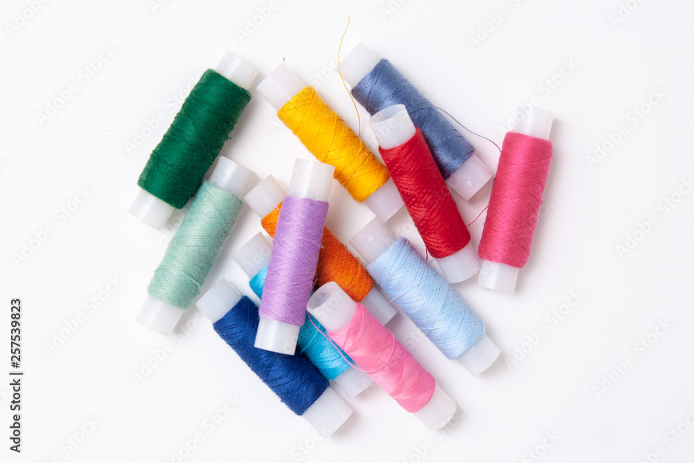 Multicolored thread coils on white background. Sewing supplies and accessories for needlework, stitching, embroidery. copyspace. flat lay. top view Multicolored thread coils on white background. Sewing supplies and accessories for needlework, stitching, embroidery. copyspace. flat lay. top view