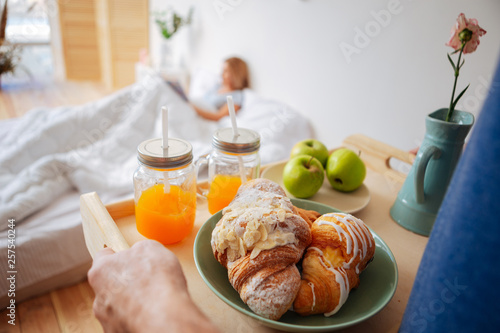 Husband making surprise bringing breakfast and flowers for wife