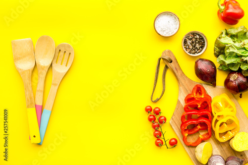 Vegan food cooking with raw vegetables on yellow background top view