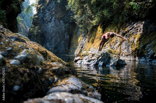 Woman in bikini diving into water from rock photo