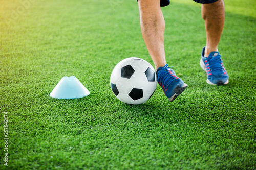 soccer player put blue sport shoes to jogging with trap and control football between cone markers
