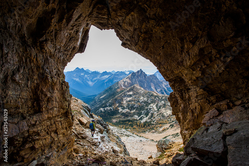 A climber stands at the mouth of a cave in the Pasayten Wilderness and the North Cascades of Washington at sunset. photo