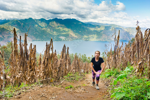 A young, athletic woman climbs up the trail of the San Pedro Volcano with Lake Atitlan in the background. photo