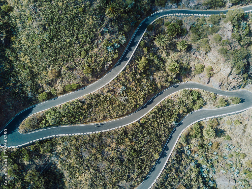 Aerial view of cyclists pedaling on winding road, Tenerife, Canary Islands, Spain Aerial view of cyclists pedaling on winding road, Tenerife, Canary Islands, Spain