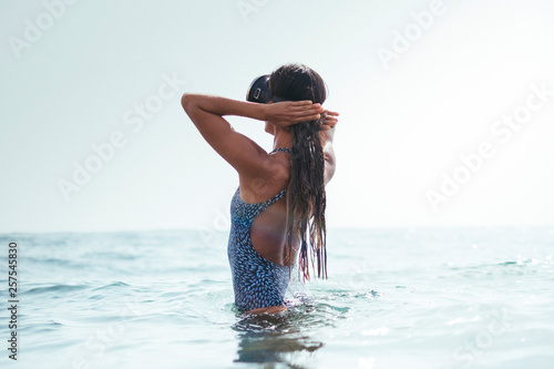 woman in a swimsuit and diving googles playing with the waves on the beach