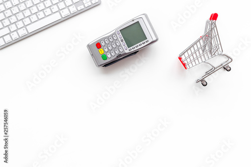 making purchase online with keyboard, card machine and mini trolley on office desk background top view mockup