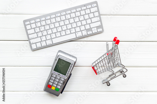 making purchase online with keyboard, card machine and mini trolley on office desk background top view
