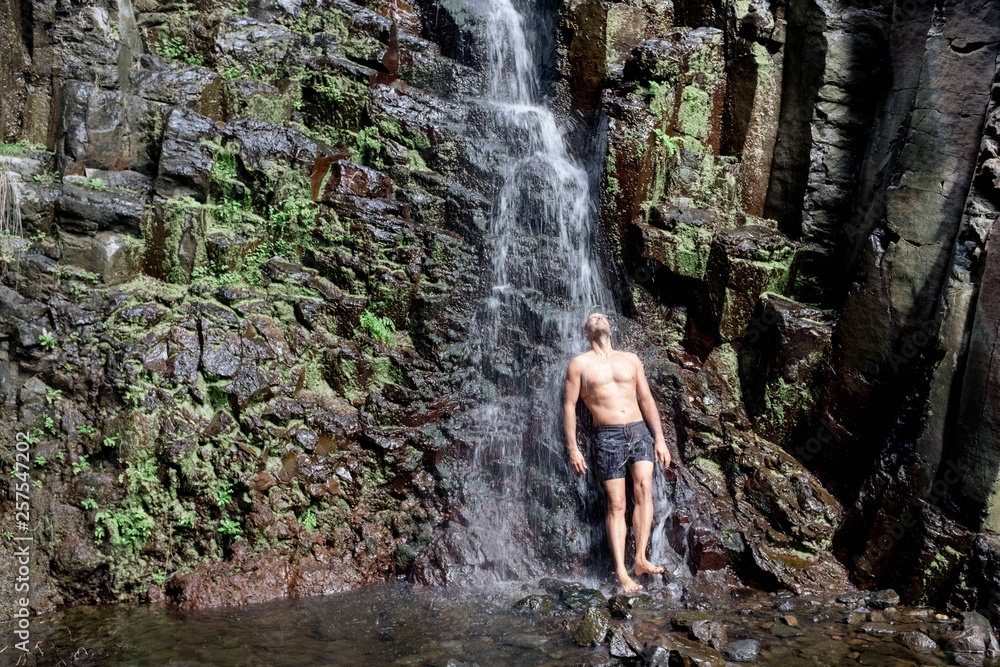 Man standing under waterfall, La Gomera, Canary Islands, Spain Man standing under waterfall, La Gomera, Canary Islands, Spain