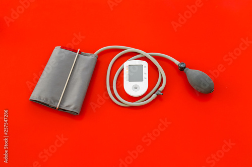 pulsimeter on the desk of the doctor for diagnostics of cardiac disease on red background top view space for text