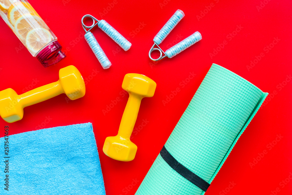 Fitness background with sport equipment for gym and home on red background top view Fitness background with sport equipment for gym and home on red background top view