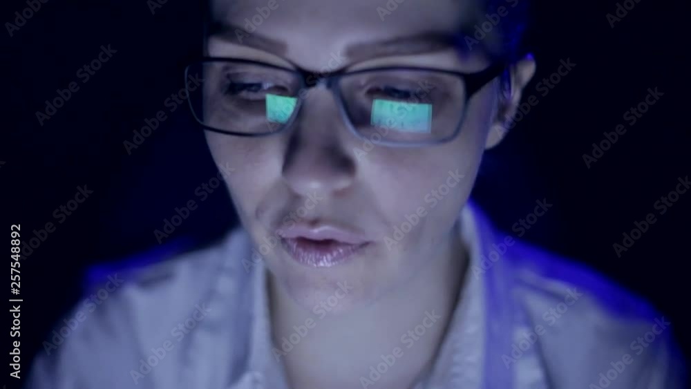 later a woman working at a laptop, monitor reflection in the glasses later a woman working at a laptop, monitor reflection in the glasses