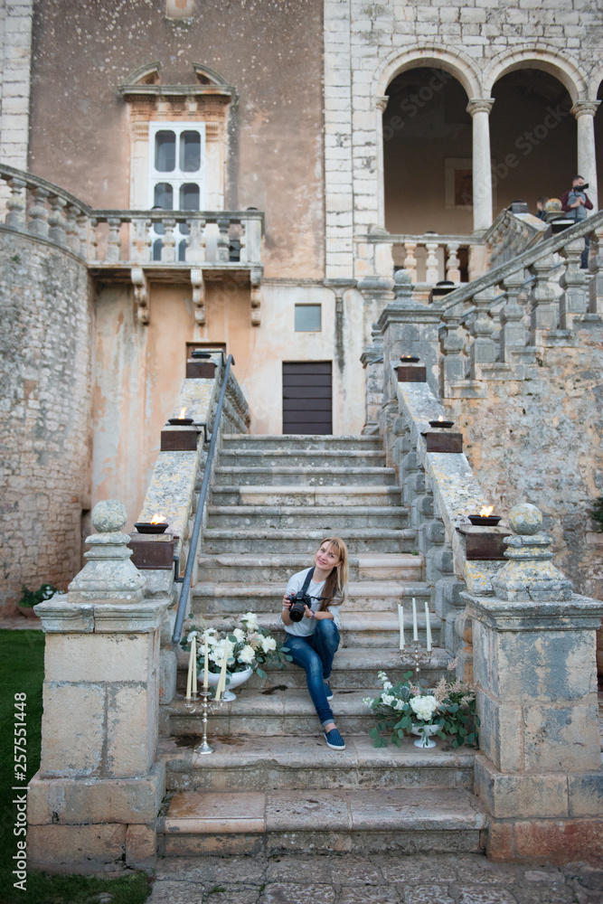 Bari, Puglia, Italy, 07 November 2018: Young romantic tourist girl sitting on the old stone stairs in the castle garden