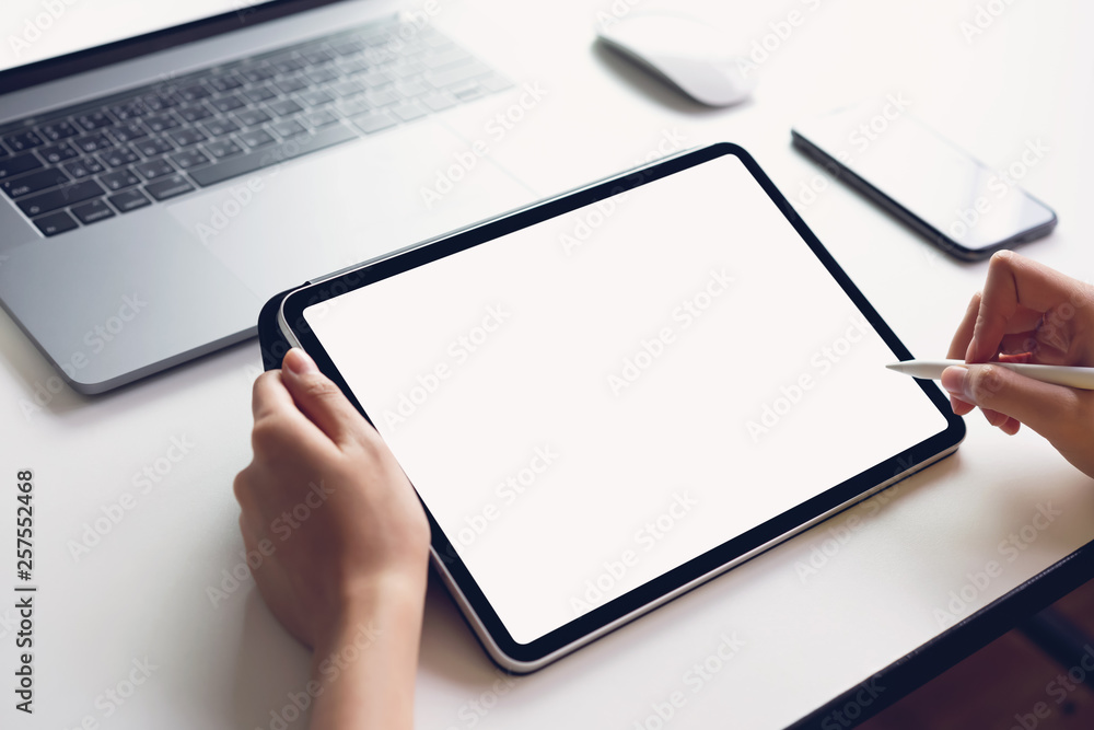Woman using tablet screen blank and laptop on the table mock up to promote your products. Concept of future and trend internet for easy access to information. Woman using tablet screen blank and laptop on the table mock up to promote your products. Concept of future and trend internet for easy access to information.