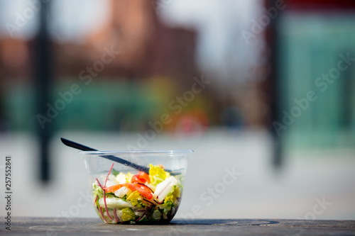 lunch salad with fork in plastic box on wooden banch