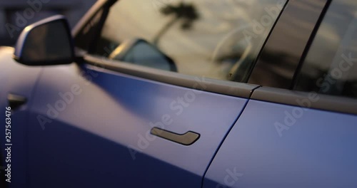 Stylish young woman shuts door of fancy sports car - side profile