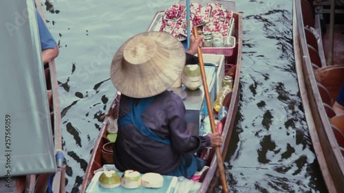 Woman in a round hat swims in a floating market in Thailand