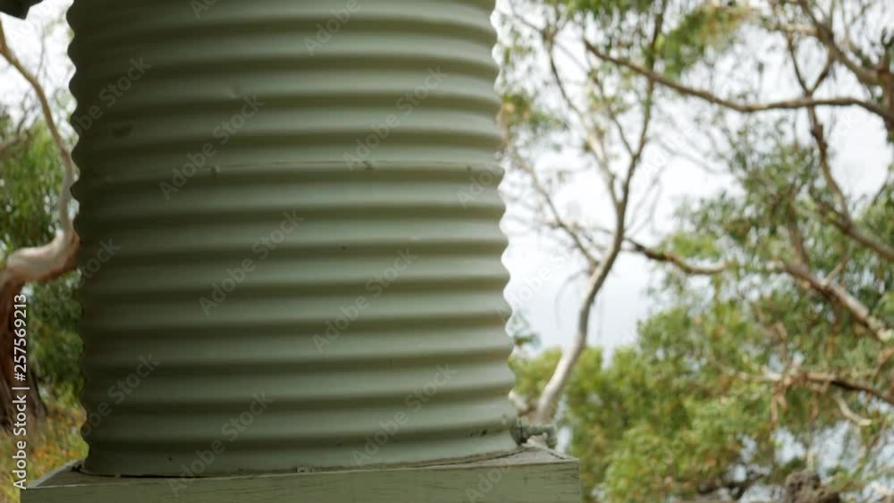 Green water tank standing alongside a freestanding gazebo. Rainwater collected from the rooftop is transferred into the catchment container. PAN UP SHOT. Green water tank standing alongside a freestanding gazebo. Rainwater collected from the rooftop is transferred into the catchment container. PAN UP SHOT.