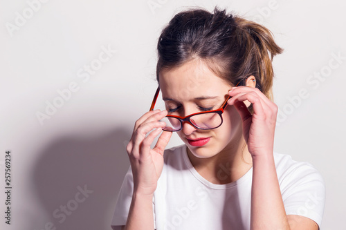 Tired young woman taking off her glasses.