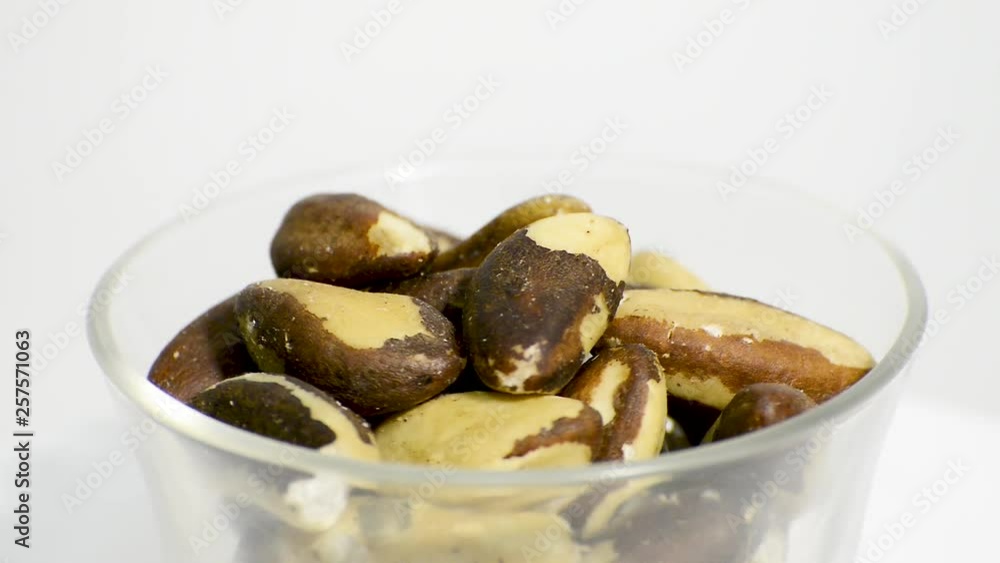 Transparent glass bowl with Brazil nuts rotating on a white background. Flat plane. High angle shot Transparent glass bowl with Brazil nuts rotating on a white background. Flat plane. High angle shot