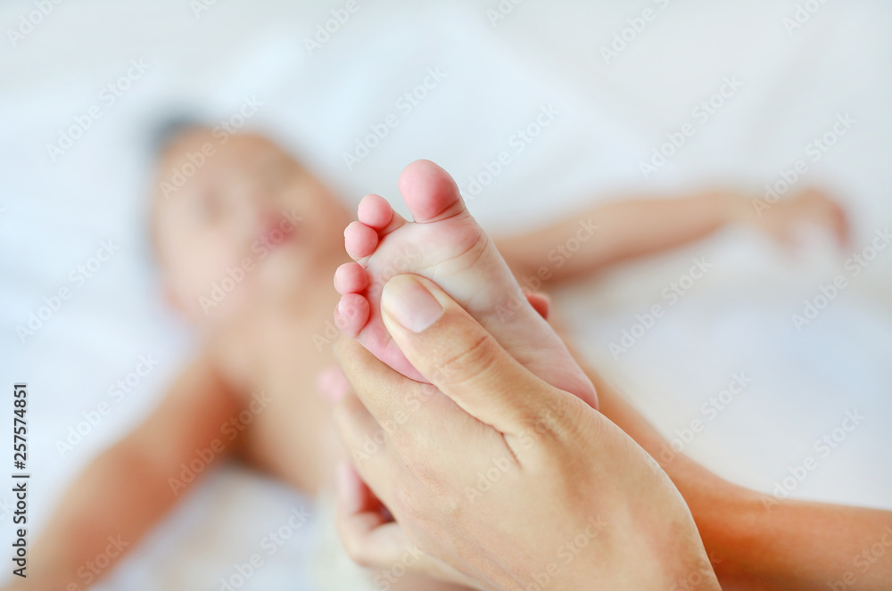 Mother hand massaging feet of infant baby on the bed at home. Mother hand massaging feet of infant baby on the bed at home.