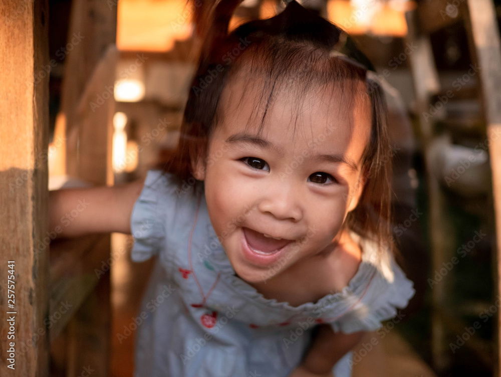 Asian little girl playing peek-a-boo with her mom with sunlight in a summer day. Relaxation travel concept. Asian little girl playing peek-a-boo with her mom with sunlight in a summer day. Relaxation travel concept.